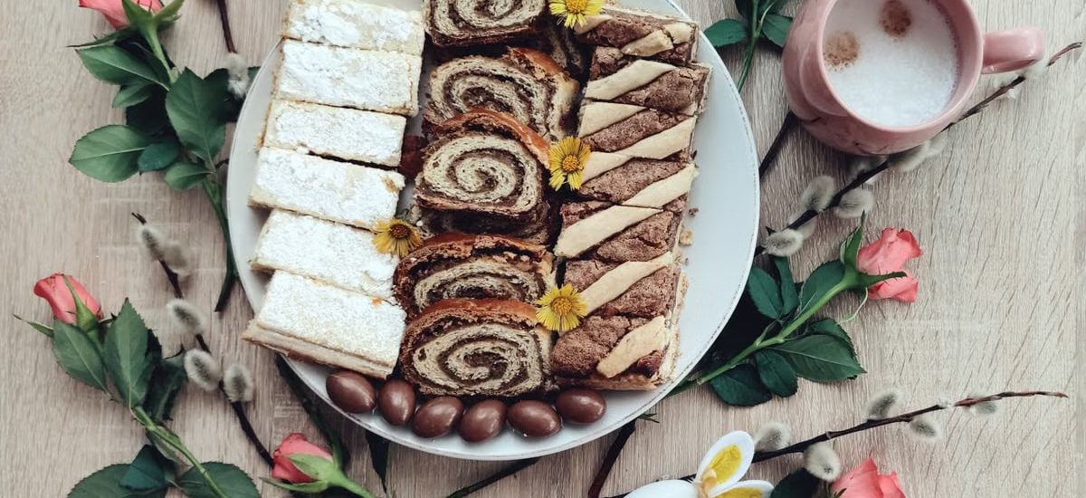 Top view of Easter desserts on a plate with coffee and spring flowers for a festive setting.