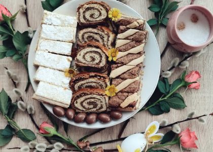 Top view of Easter desserts on a plate with coffee and spring flowers for a festive setting.